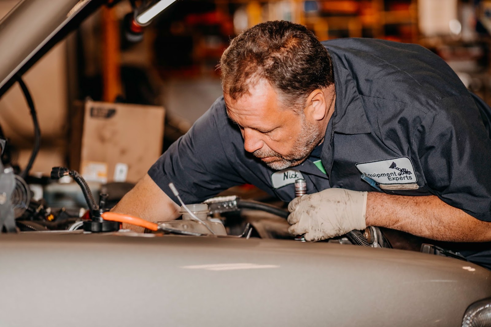 A close-up of an employee with his hands in the guts of a vehicle