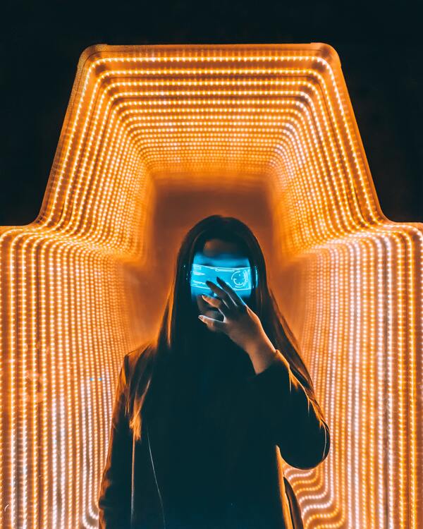 homem com capuz e um óculos cibernético e um fundo com cores laranja em neon 