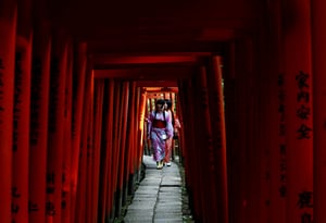 Women dressed in yukata, casual summer kimonos, walk through torii gates at the Nezu shrine, Tokyo, Japan