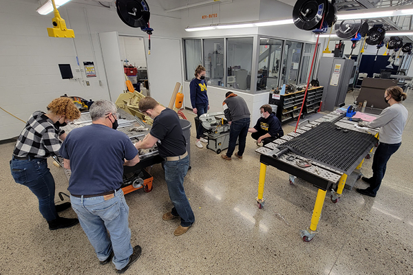 Students work on assembling a rover at different tables in Murchie Science Building Machine shop. 