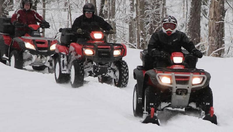 Gear up for an adventure in the great outdoors with a snowmobile and a couple of ATVs taking on a snow-covered trail