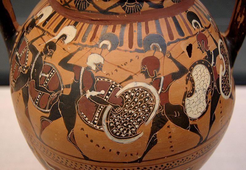 Greek hoplites facing each other in battle painted on a clay vessel. They are wearing helmets with pronounced plumes and large shields. They are armed with spears.