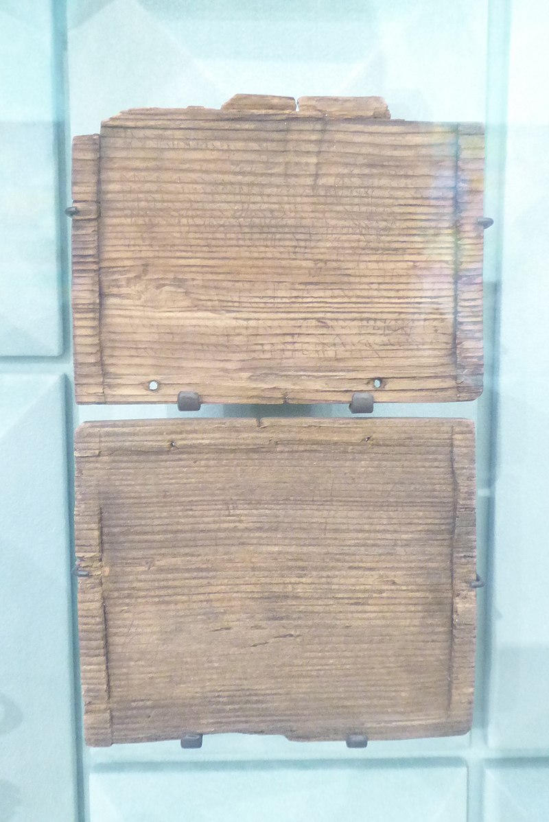 A simple wood tablet missing its wax, show with the holes where the binding once was.