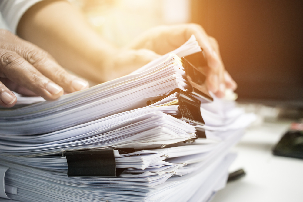 View of hands sorting through stack of paper files.