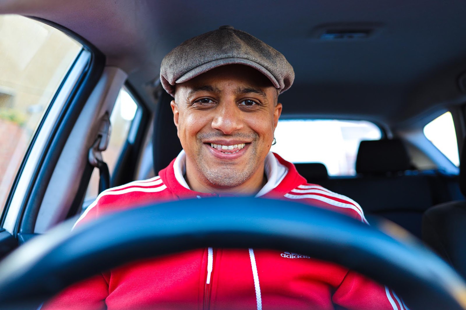 [Alt. Text: A picture of a person smiling while driving their car, knowing they have protection with CarGuard Administration.]