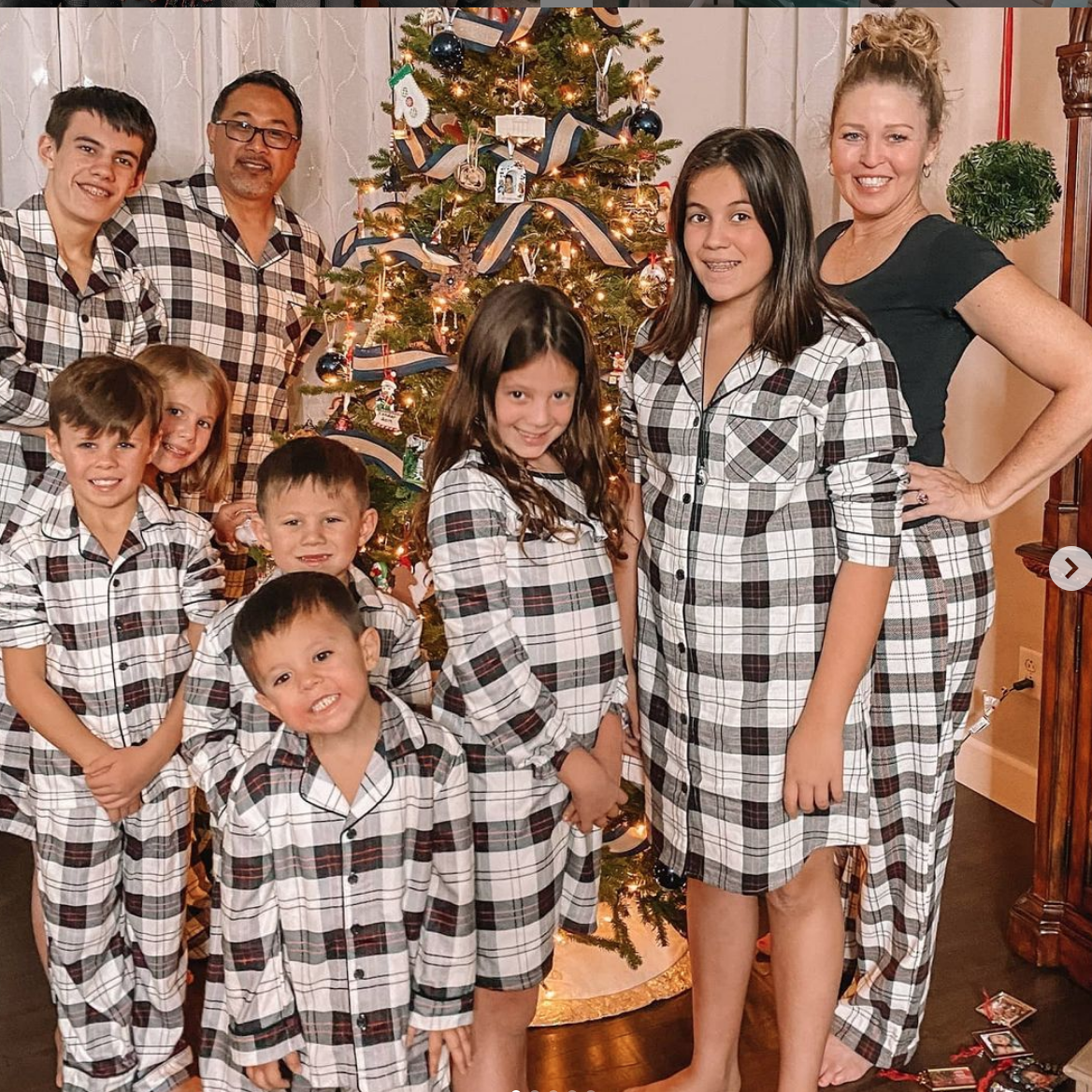 couple adopts 7 siblings and spends a winter night together in front of a decorated tree, wearing match pj's