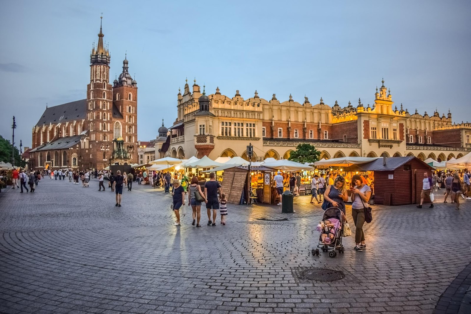 krakow main market square touristic market and tourists basilica in background during sunset