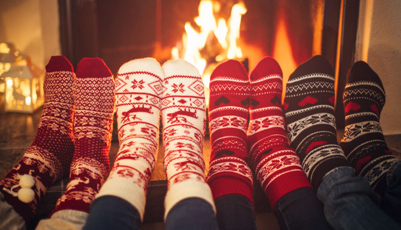 A group of people wearing winter socks and warming their feet by the fire