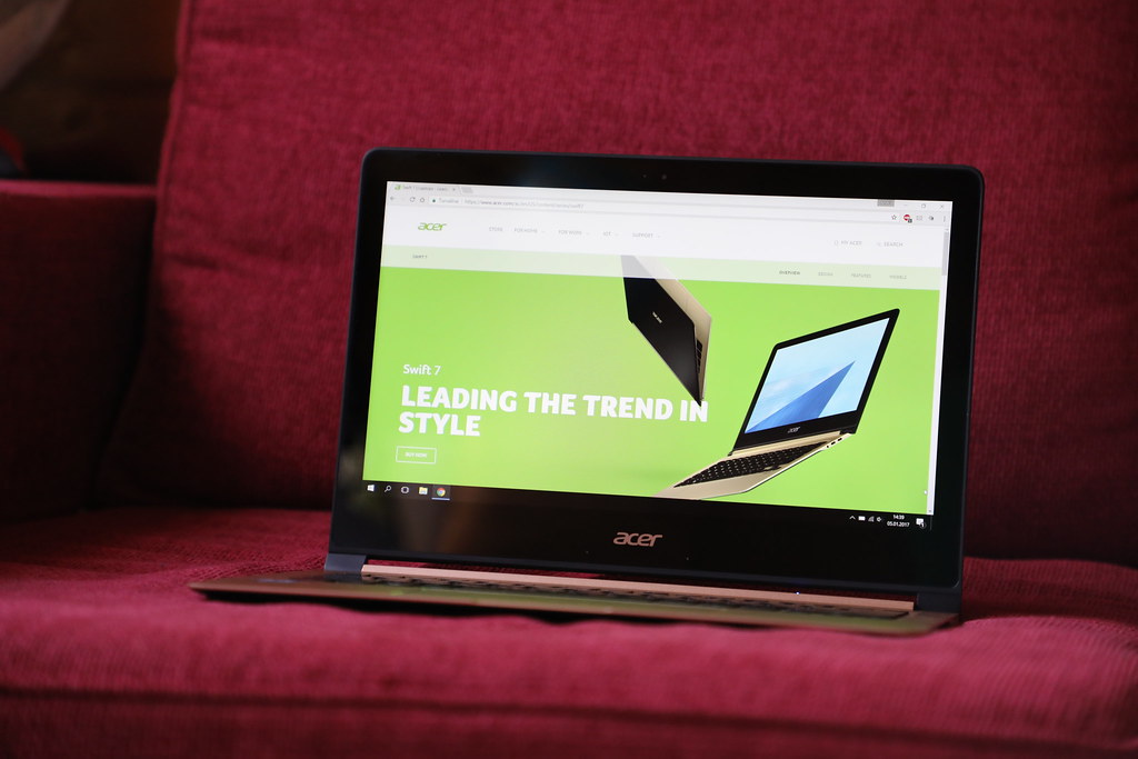 This image shows the Acer Laptop with open display is in the red sofa.