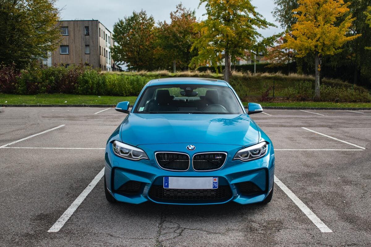 Una BMW blu parcheggiata in un parcheggio a strisce bianche