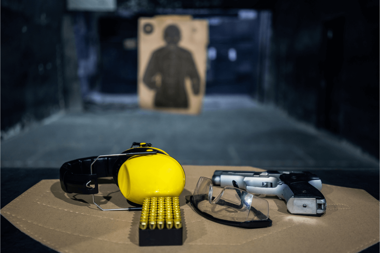 Firearm and bullets, along with shooting range protection, are sitting in a booth at a shooting range