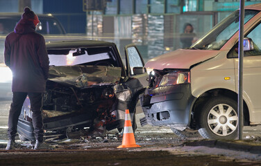 Cars crashed heavily in road accident after collision and silhouette of people on city street at night. Road safety and insurance concept