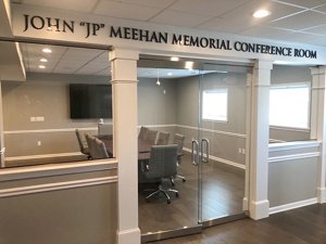 Looking through glass doors at an empty John 'JP' Meehan Memorial Conference Room with a conference table surrounded with Harper Mid-Back Chairs