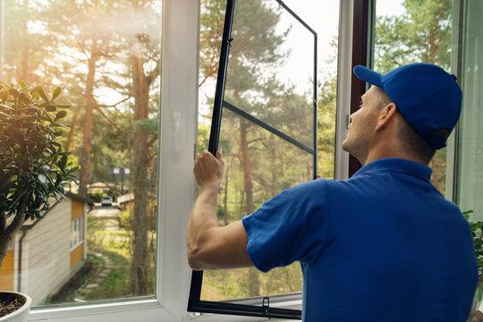 WeServe | a man with a blue shirt and hat changing a broken window with a background full of trees