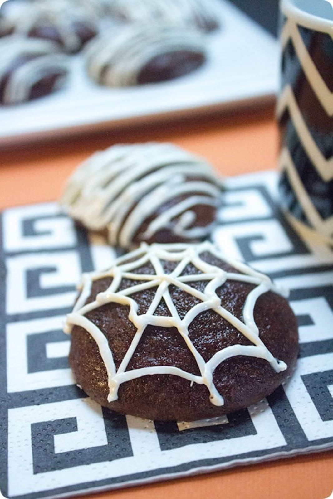Brownie cookies decorated with a white spiderweb on top using icing.