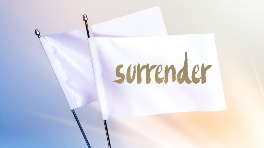 Surrender is written on a white flag. How to surrender using affirmations to let go of control. written by Deliapg