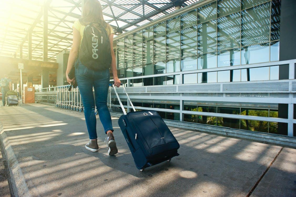 woman walking through airport with suitcase