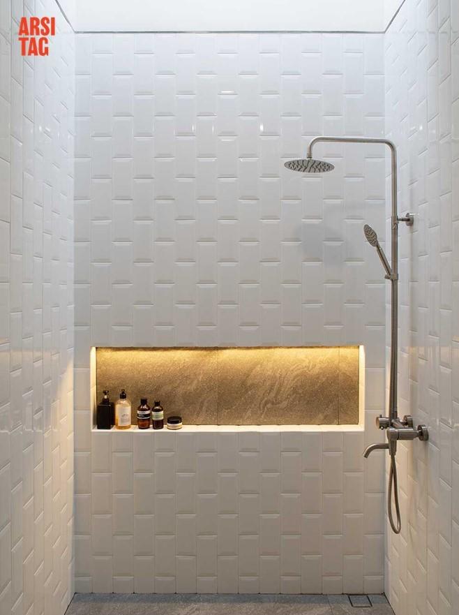 Pola pemasangan ubin dinding yang unik pada kamar mandi putih dengan sumber penerangan dari skylight, Karya Localic Studio via Arsitag