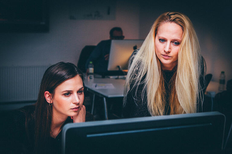 An intern working with supervisor at a workstation.