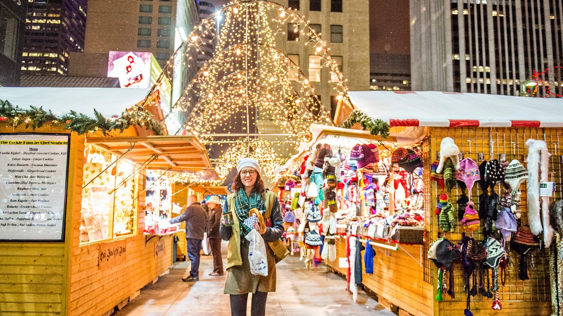 Woman in winter clothes standing between vendors at German-style holiday market. A favorite winter event in Denver.