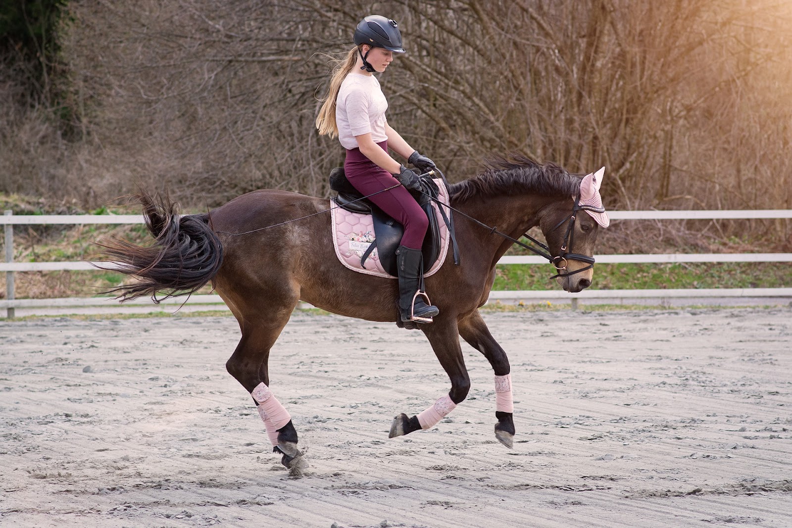 female rider with pink saddle pad performs a flying lead change