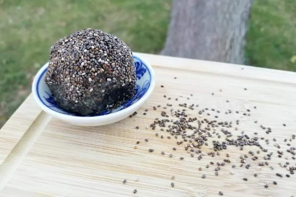 Black protein balls shown on a wooden cutting board.