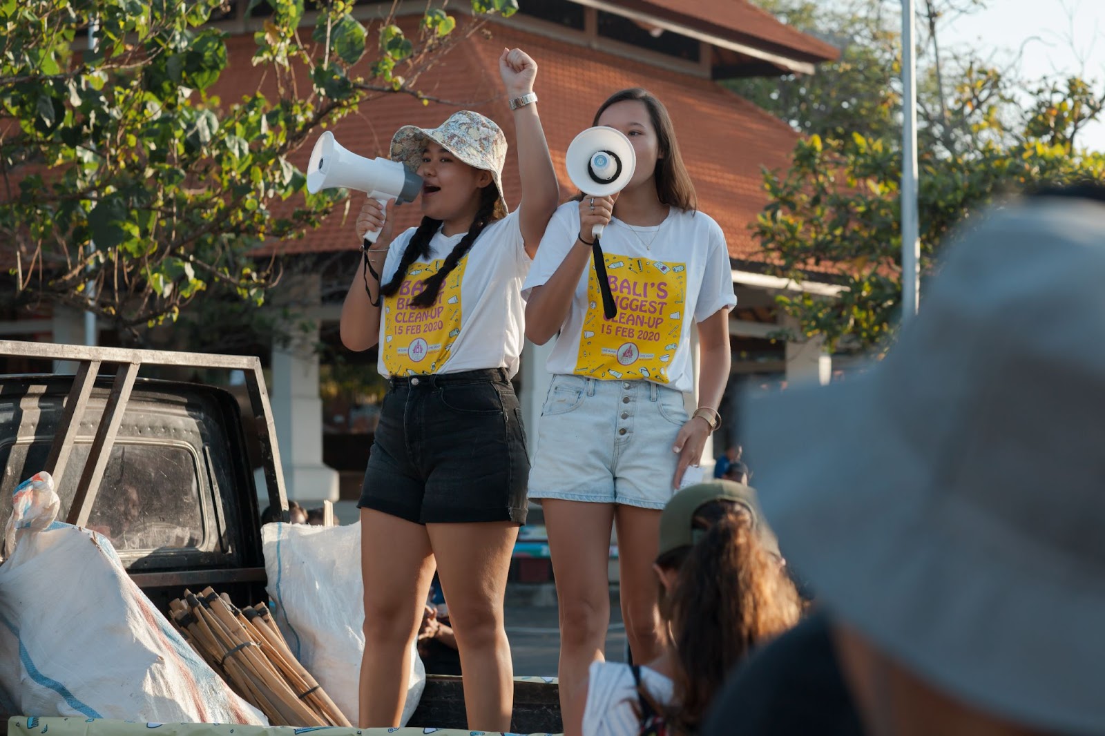 Klimaatactiviste Melati staat samen met haar zusje op een auto en roept door een megafoon tijdens de Bali's Biggest Clean Up.