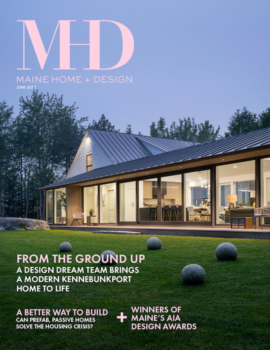 The cover for a home and garden magazine - Maine Home + Design. The cover shows a beautifully lit-up modern home and garden at dusk.