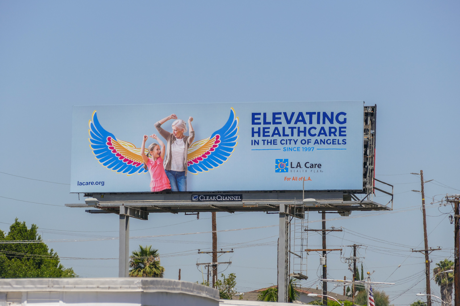 LA Care billboard with an old woman and a kid dancing with wings behind them, with the text "Elevating healthcare in the city of angels since 1997"