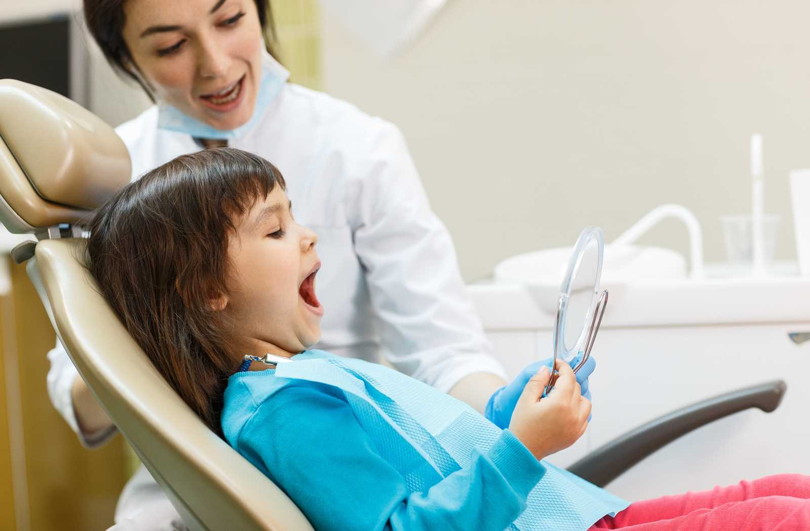 Young child looking at mirror in dentist chair