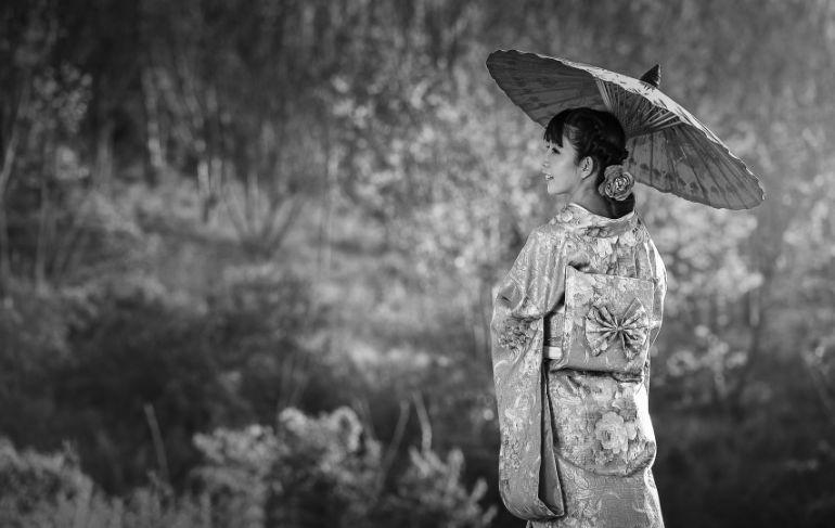 Chinesa com um guarda chuva sorrindo