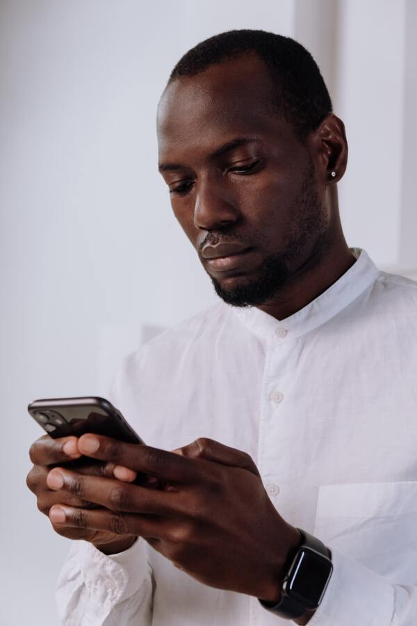 homem negro sentado e mexendo no celular