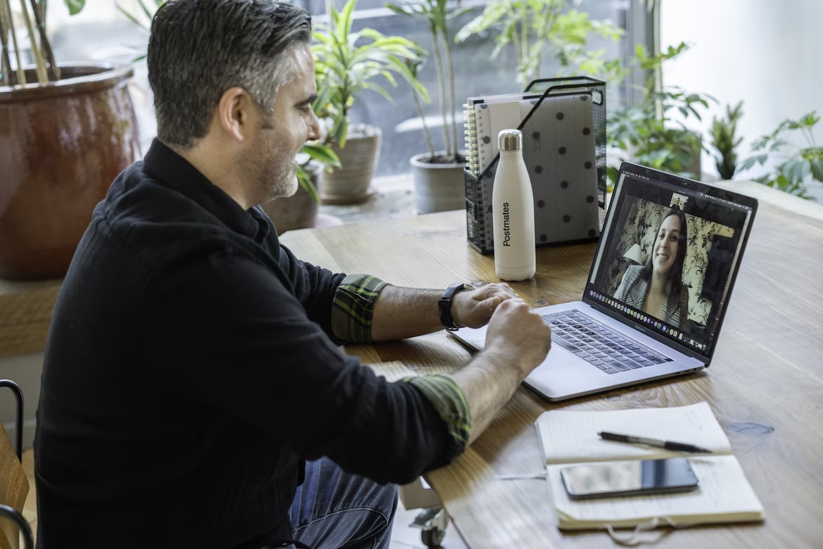 Como fazer consultoria financeira: homem em videoconferência com uma mulher por meio de notebook