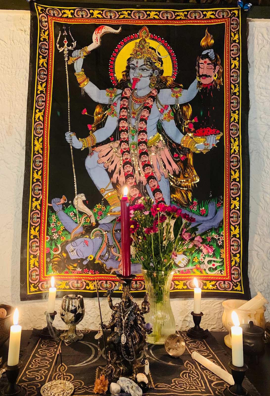 There is a tapestry of Kali on the wall, as well as candles and flowers arranged in front of it: it's an altar to Kali.  