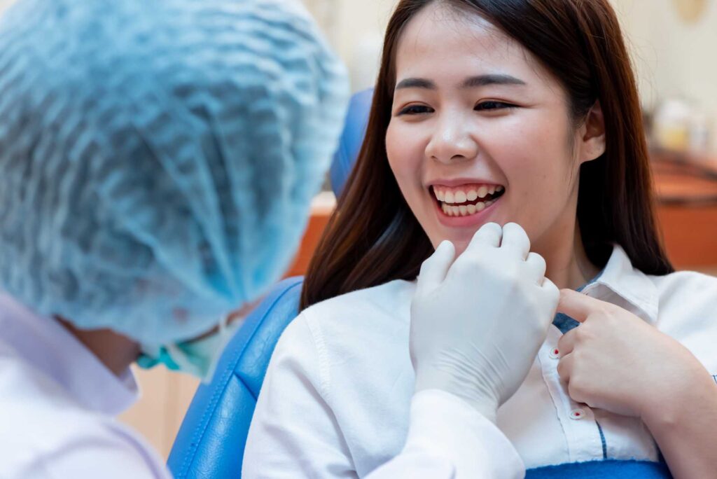 05 A young patient smiling broadly in front of a dentist in the dental surgery