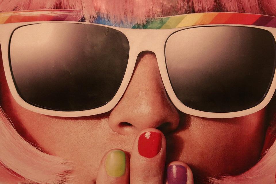 Close up of a girl with pink hair wearing rainbow sunglasses