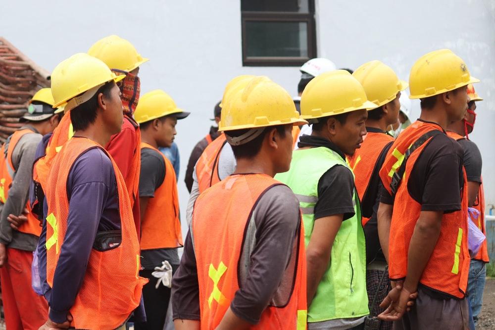 man in orange vest wearing yellow hard hat