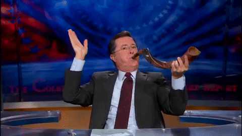 Stephen Colbert blowing a shofar waving goodbye.