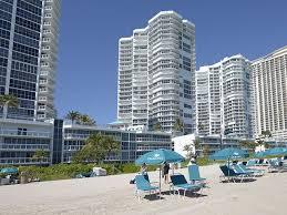 A group of people on a beach in front of a building

Description automatically generated