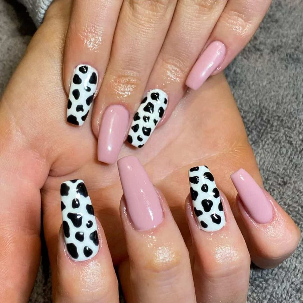 Full picture of a lady rocking a mix match of  pink and colorful cow print nails 