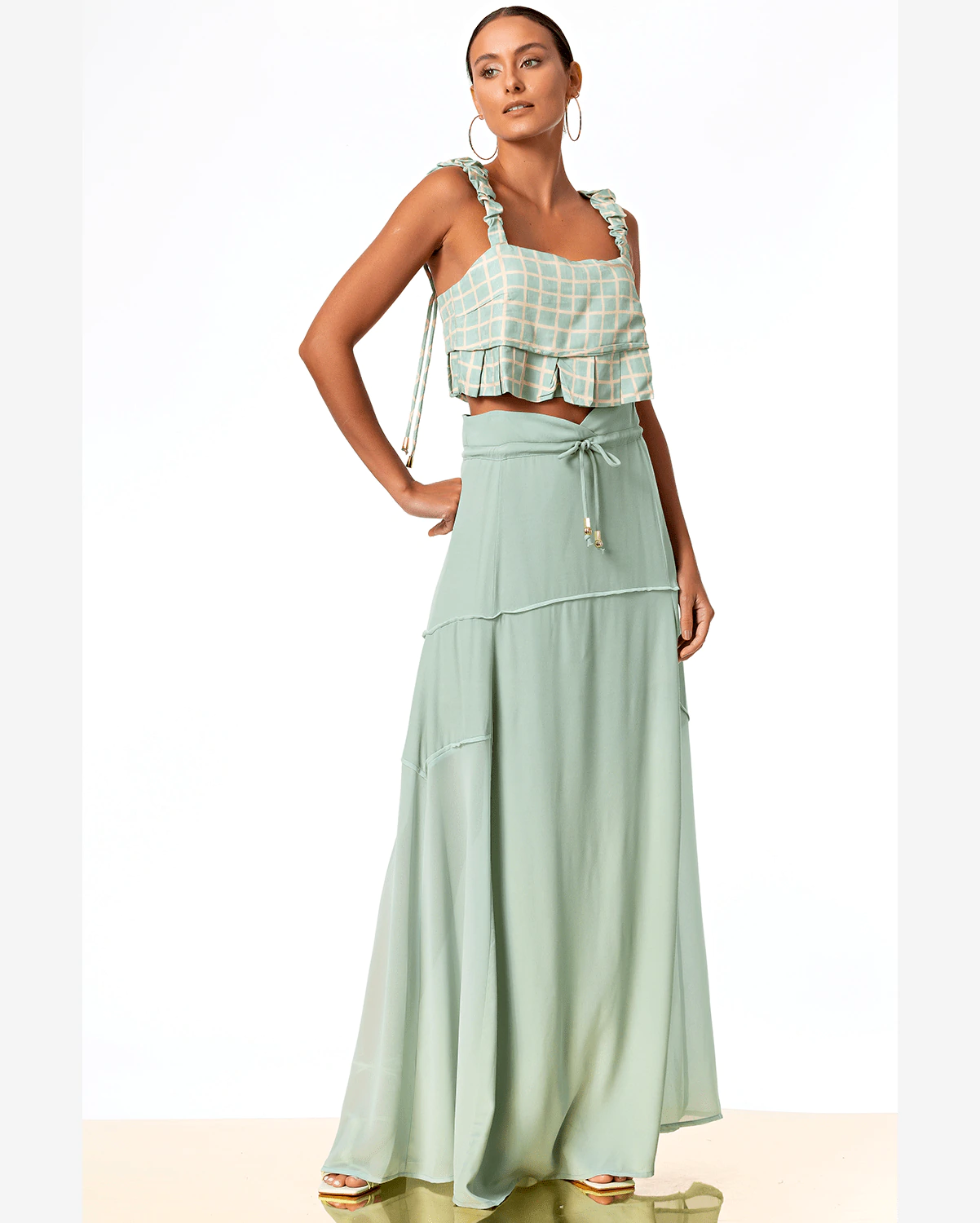 mulher usado um look com cropped e saia longa na cor verde e com recorte liso