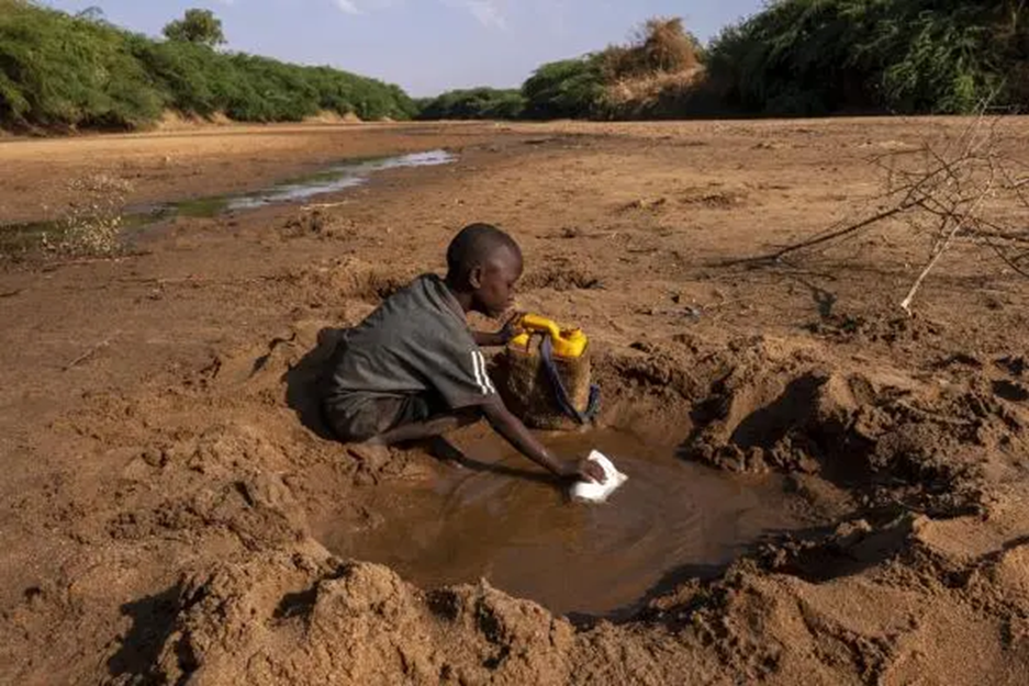 boy storing water in a container from the ground due to a water shortage
