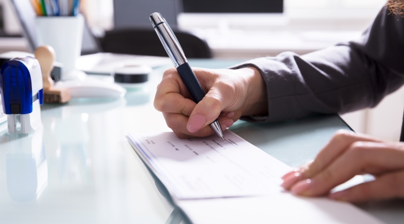 a man signs a lump sum check for a new employee's relocation package