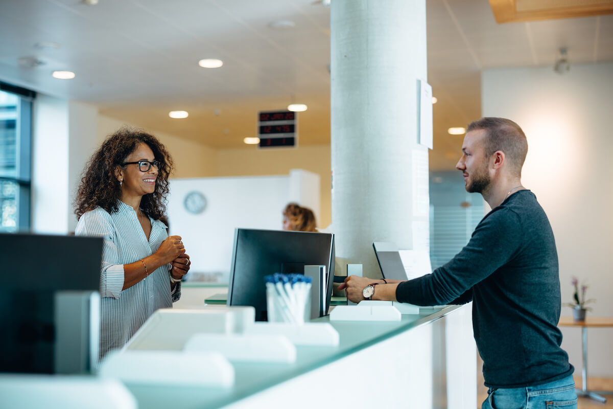 Benefits of electronic health records: man talking to a receptionist