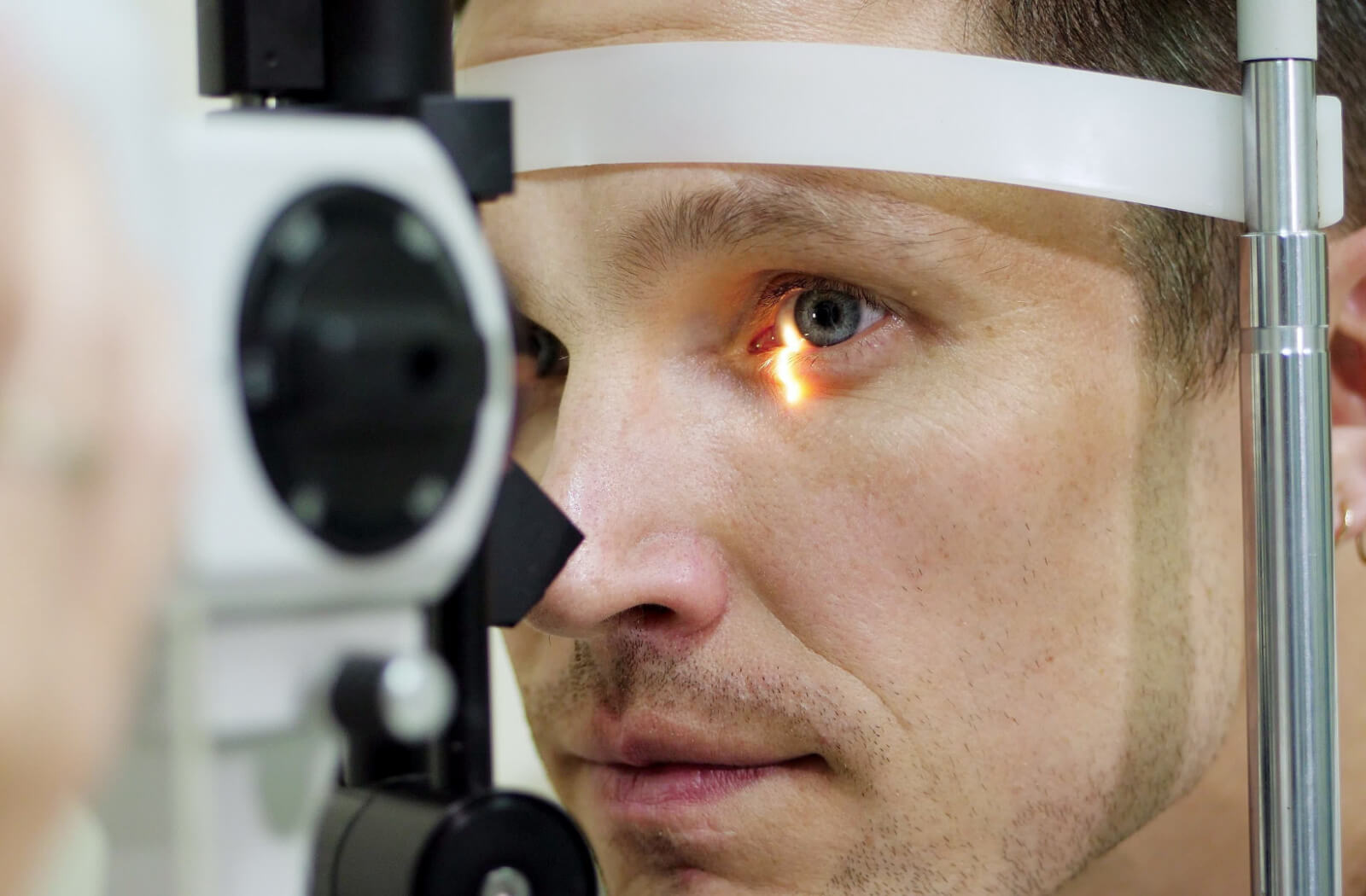 A man undergoing an eye exam with the use of an ophthalmoscope.