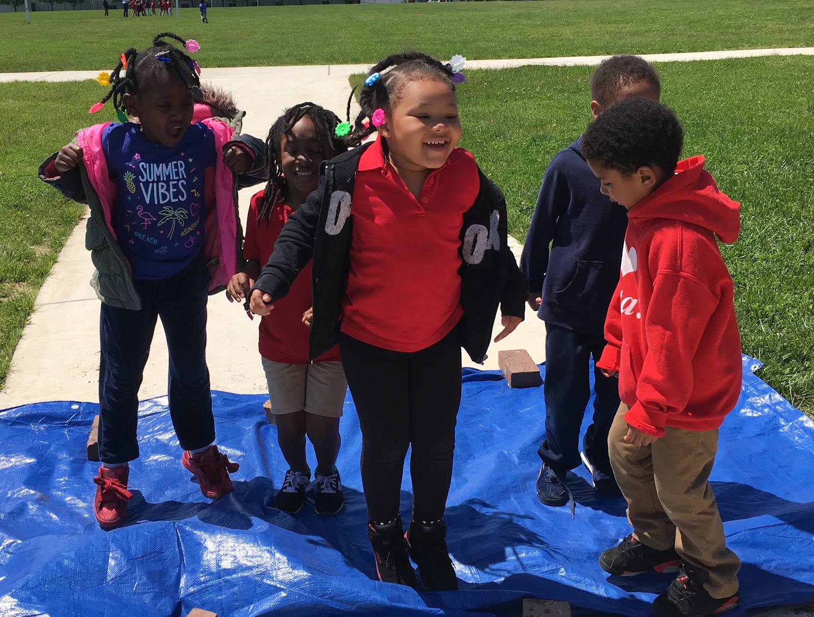 Students helping to thresh rice by jumping on it sandwiched between two tarps