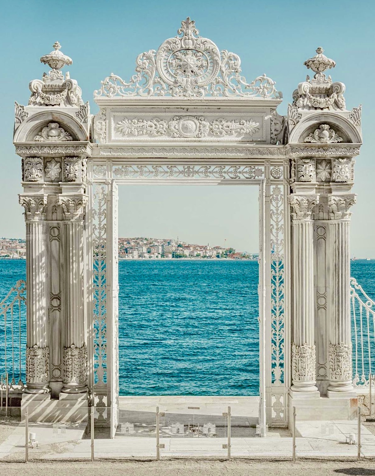 a white archway with a body of water in the background