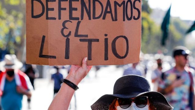 Una señora alza una pancarta que dice "defendamos el litio"