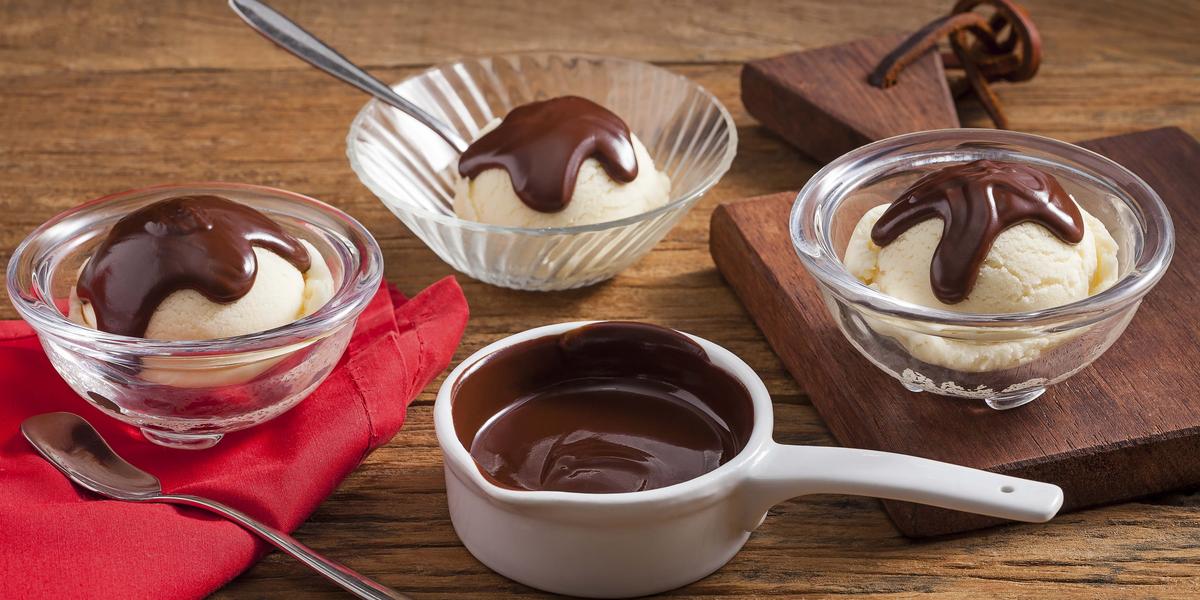 Na imagem, recipientes com bolas de sorvete cobertas por calda quente de chocolate.