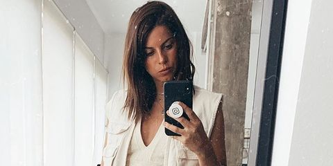 La influencer de moda Marta Riumbau se fotografía a si misma en el espejo, sosteniendo un teléfono móvil.